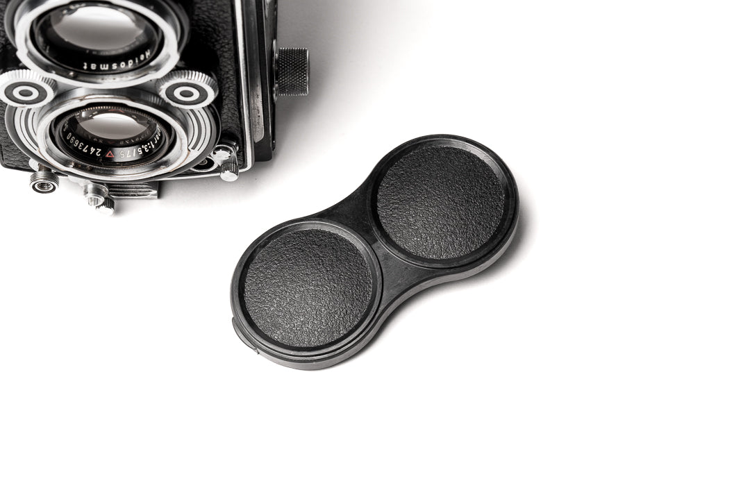 A black plastic lens cap for next to a camera. Bay 1 I Lens Cap for Rolleicord Rolleiflex Cameras.