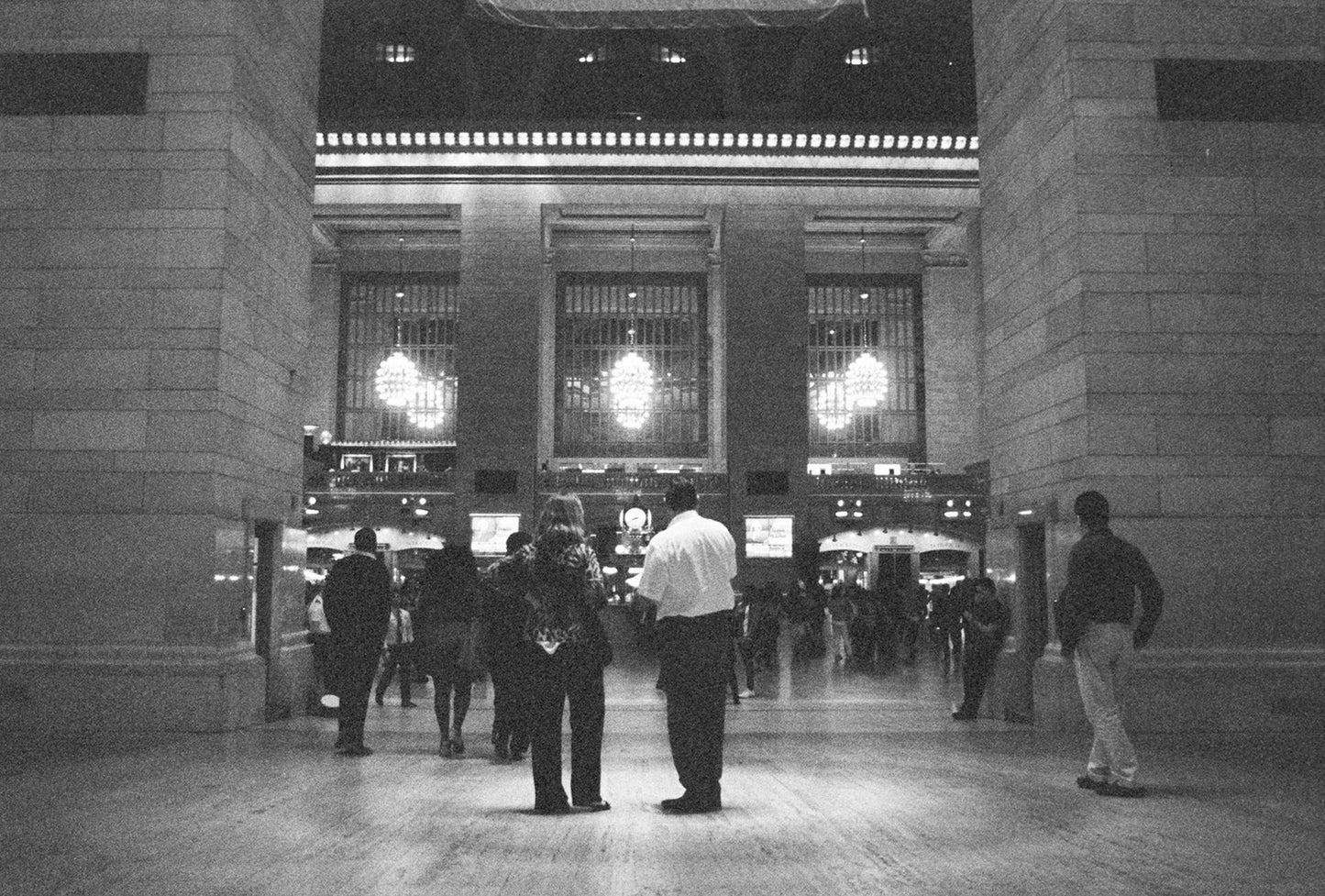 A black and white photo of people standing in the building hall.