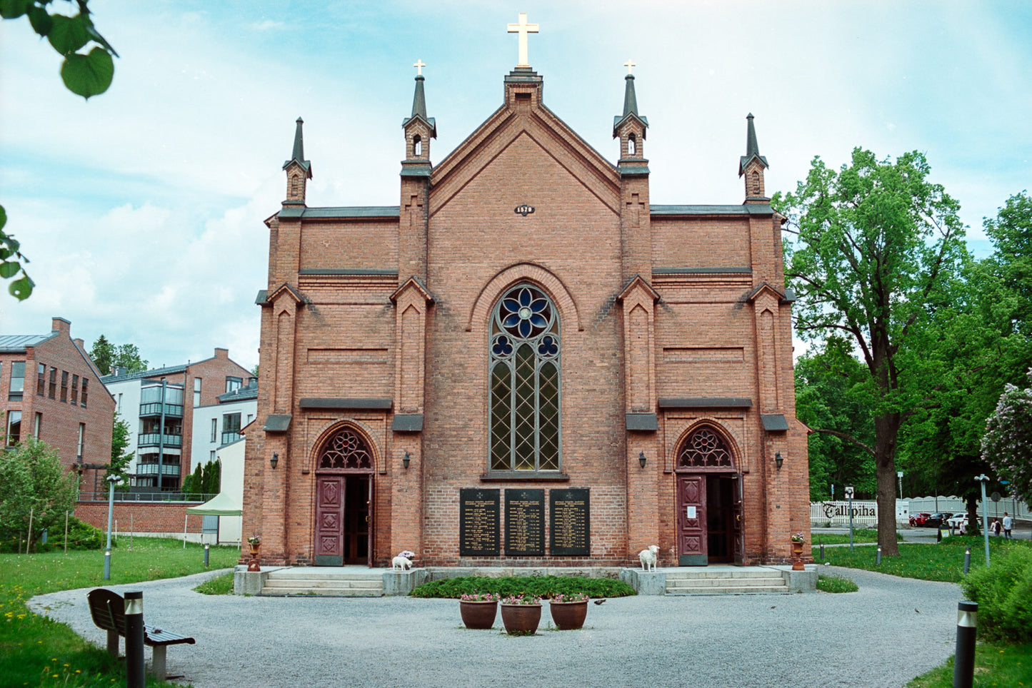 A church with some trees and buildings on the background.