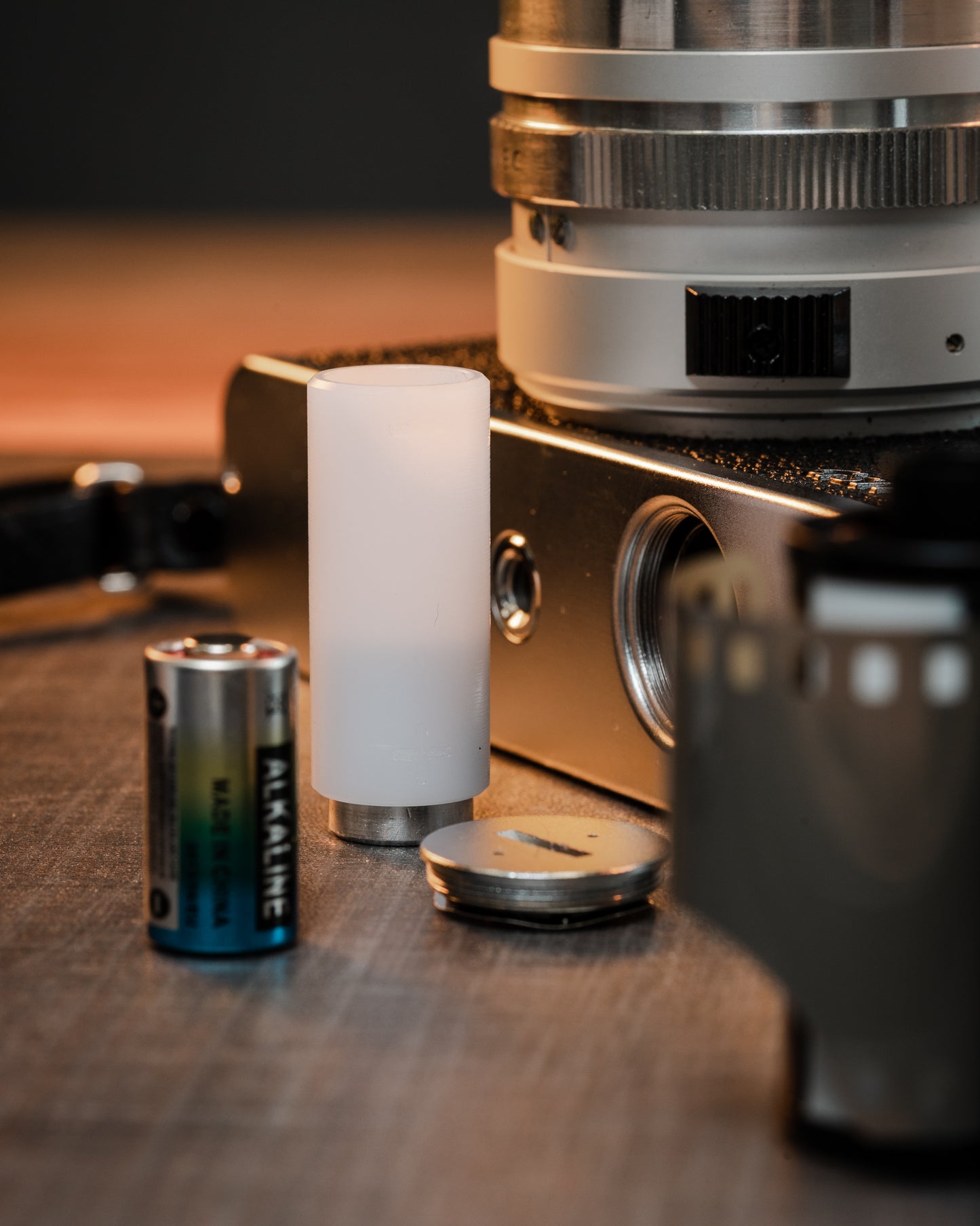 PX32 Battery Adapter with battery, camera and other accessories on a table.