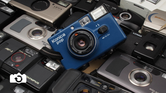 Group of point and shoot cameras with a blue konica pop in the middle
