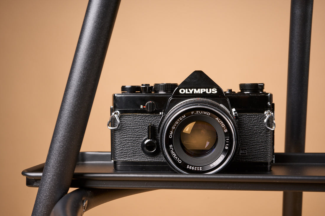 Black Olympus OM-1 film camera on a light brown background