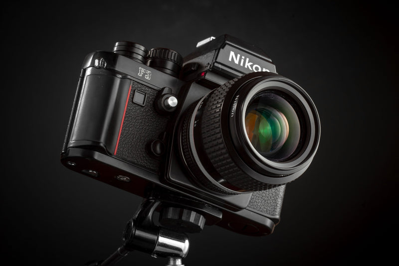 nikon f3 on tripod with light reflecting off lens