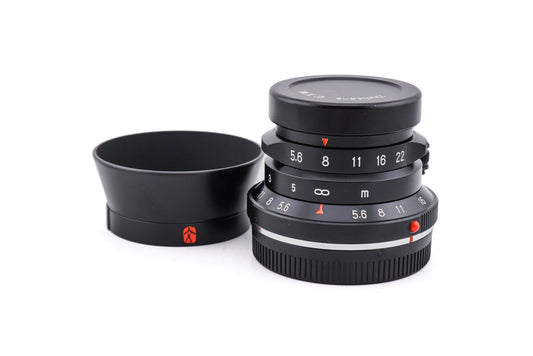 7Artisans 28mm lens with a lens cap on a white background.