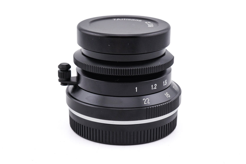 7Artisans 28mm lens with a lens cap on a white background.