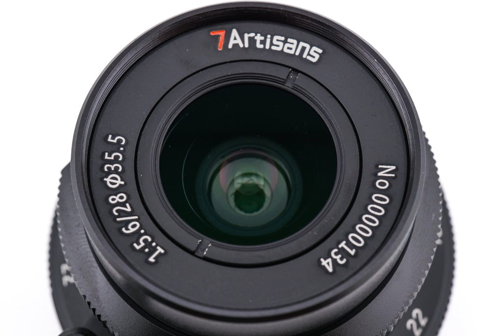 A close-up of a 7Artisans 28mm lens front on a white background.