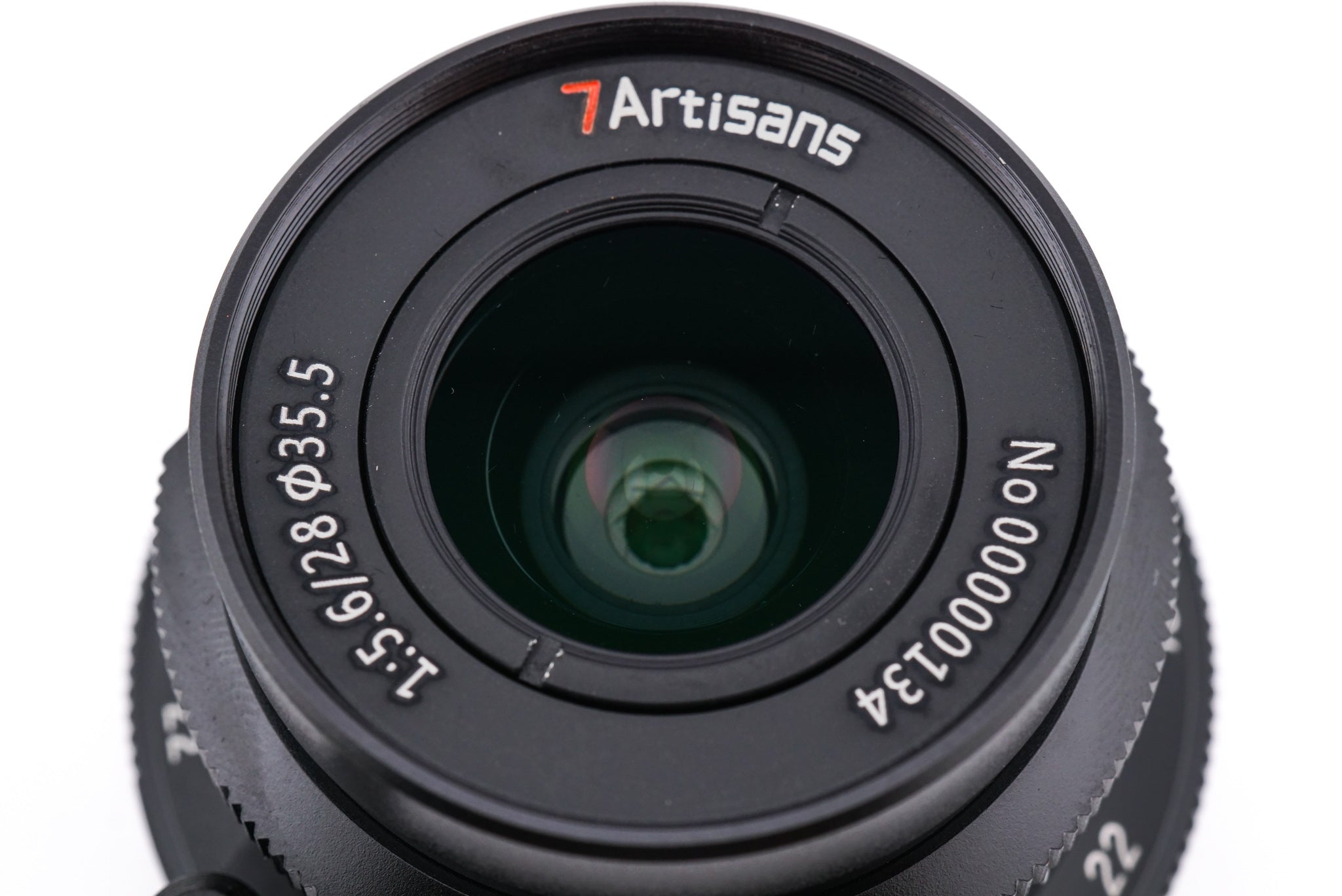 A close-up of a 7Artisans 28mm lens front on a white background.