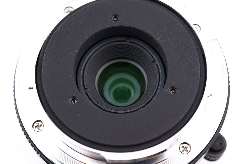 A close-up of 7Artisans 28mm lens rear on a white background.