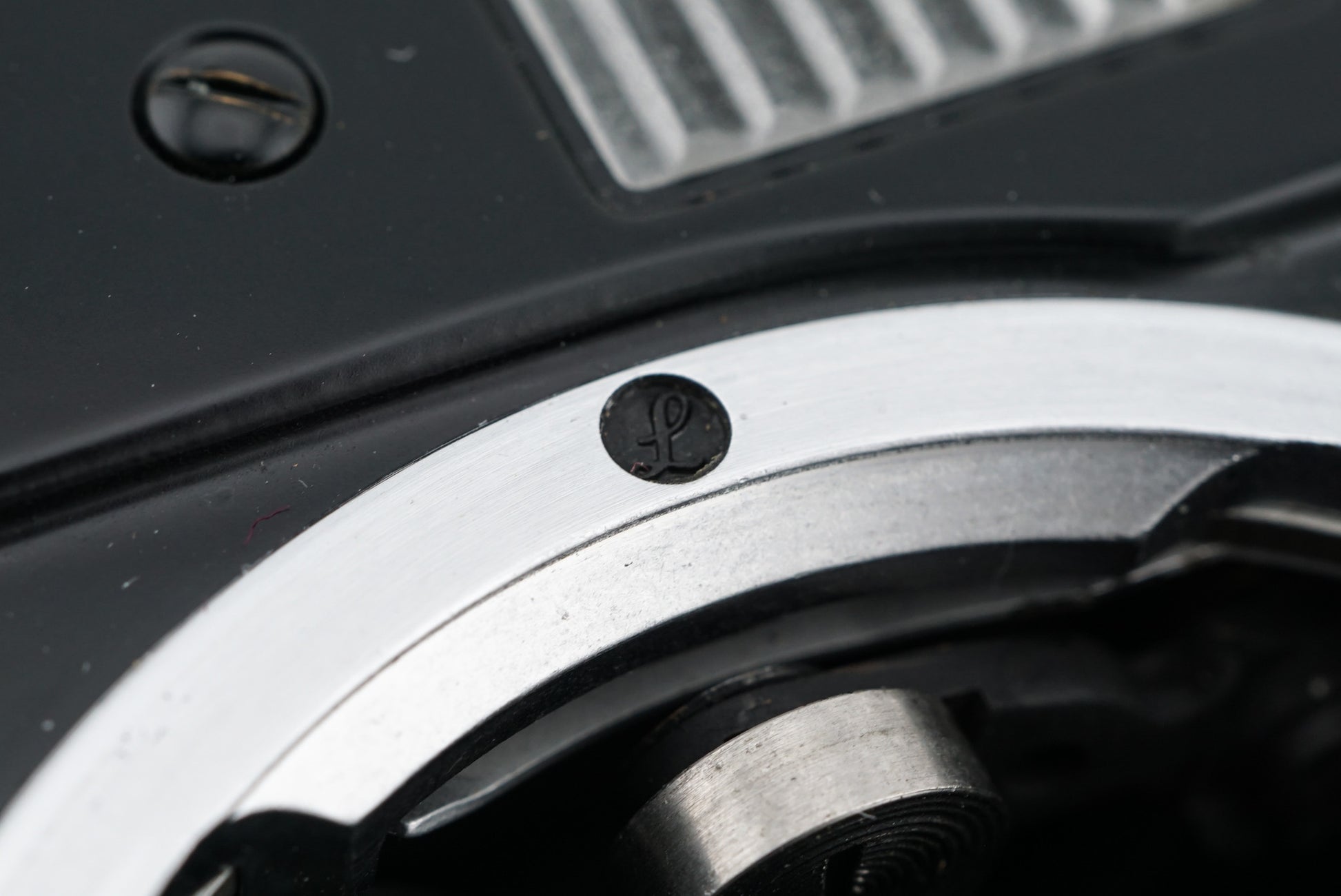 Close up macro view of original black "L Seal" located at the top center of the lens mount on a black paint Leica M4