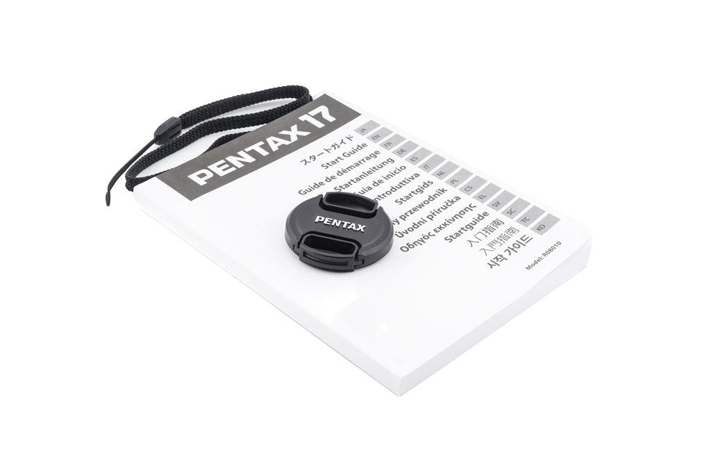 Pentax 17 half-frame camera lens cap and strap with a manual on a white background.