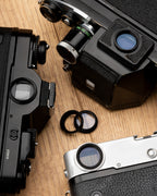Two black aluminium 19mm eyepieces on a table surrounded by camera bodies.