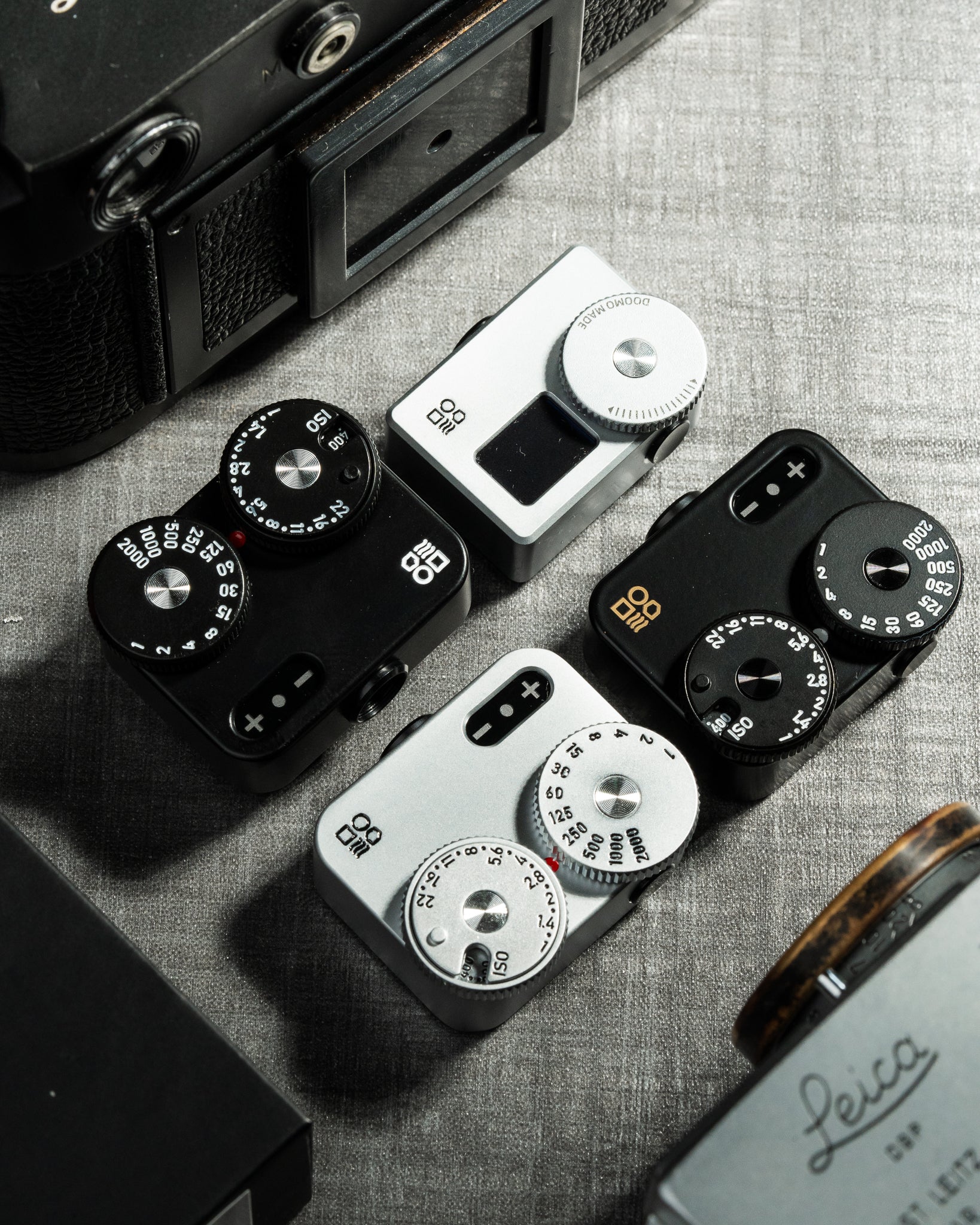 Several Doomo Meter D hot shoe light meters on a table surrounded with camera gear.  