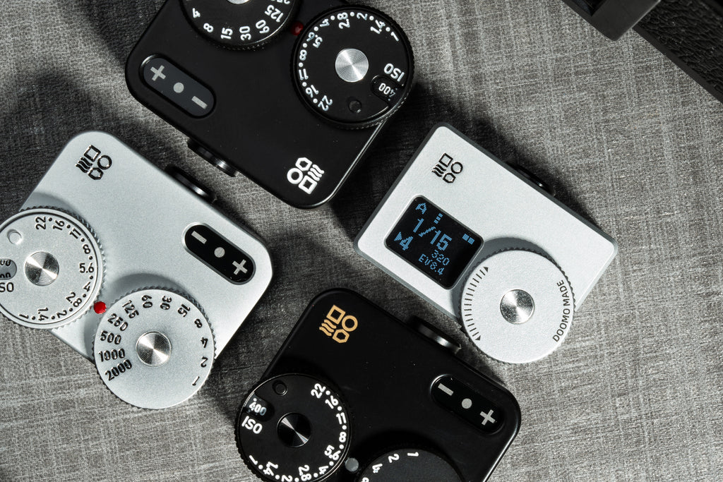 A close-up shot of several Doomo Meter D hot shoe light meters on a table. 
