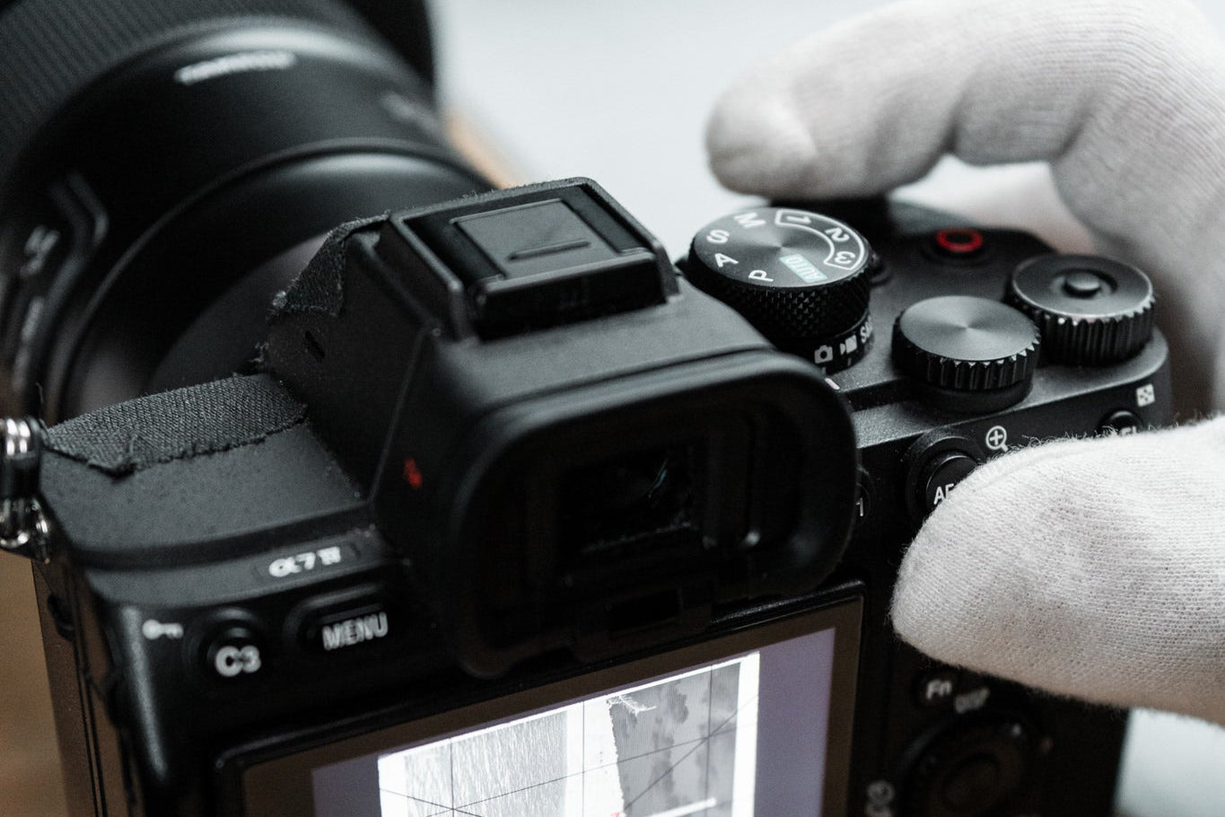 Person holding a camera with a viewfinder displaying an image on a wooden surface