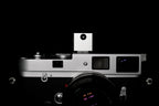 A frontal close-up of KMQ chrome model attached to a camera on a black background.