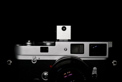 A frontal close-up of KMQ chrome model attached to a camera on a black background.