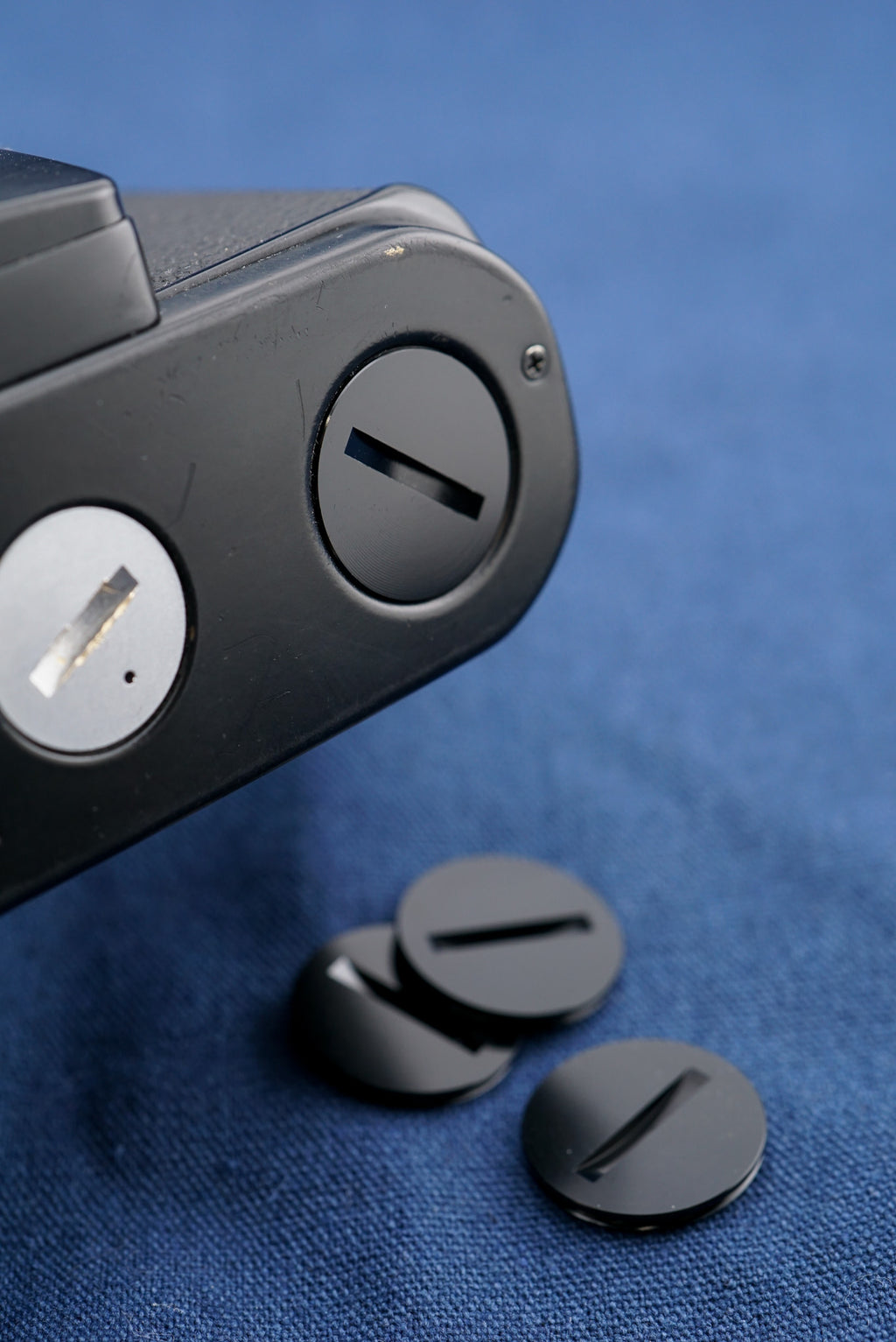 A close-up of an aftermarket motor drive coupling cover attached to a camera body on a white background. For Nikon bodies.