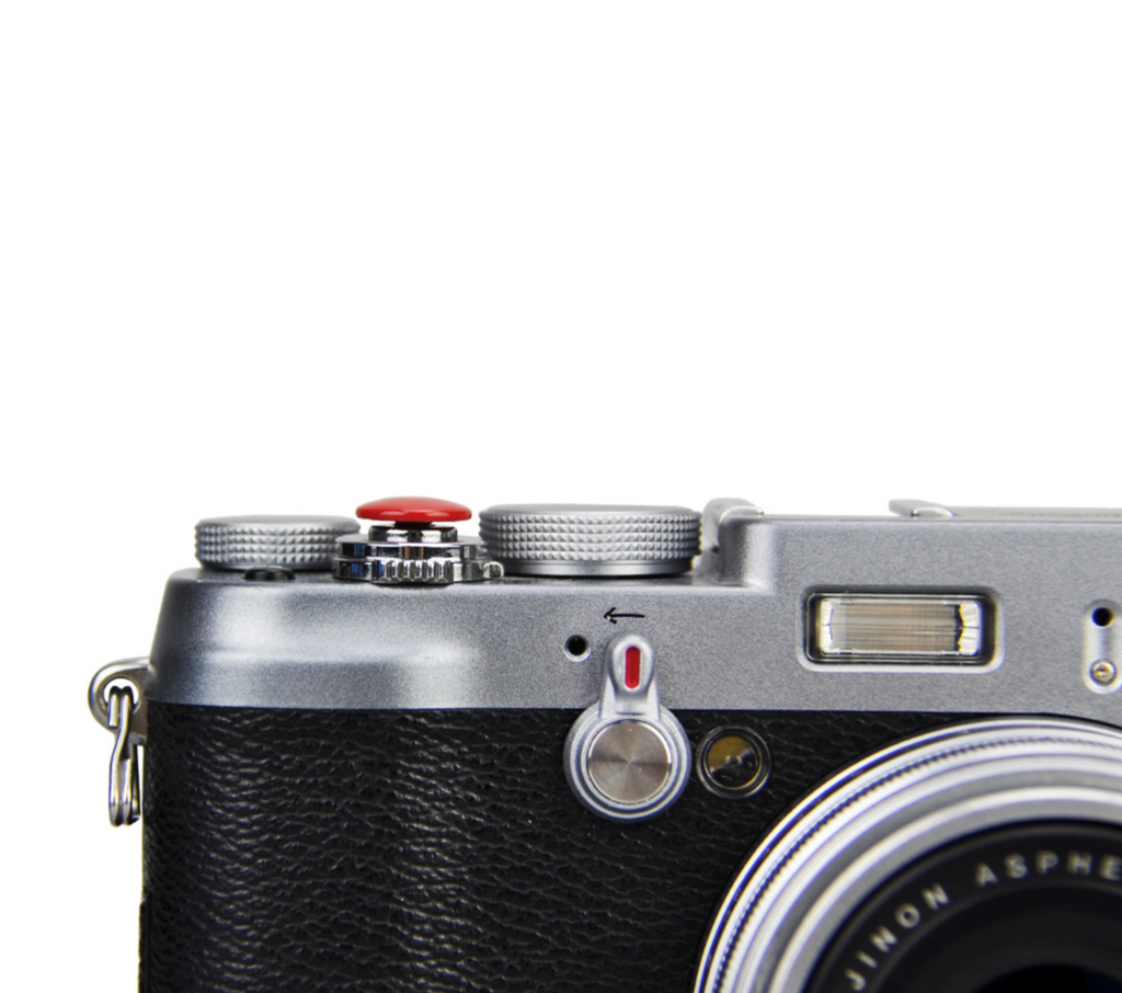 A close-up of a red JJC soft release button attached to a camera body.