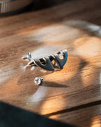 A metallic Nikon camera accessory and screws on a wooden table.