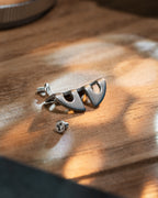 A metallic Nikon camera accessory and screws on a wooden table.