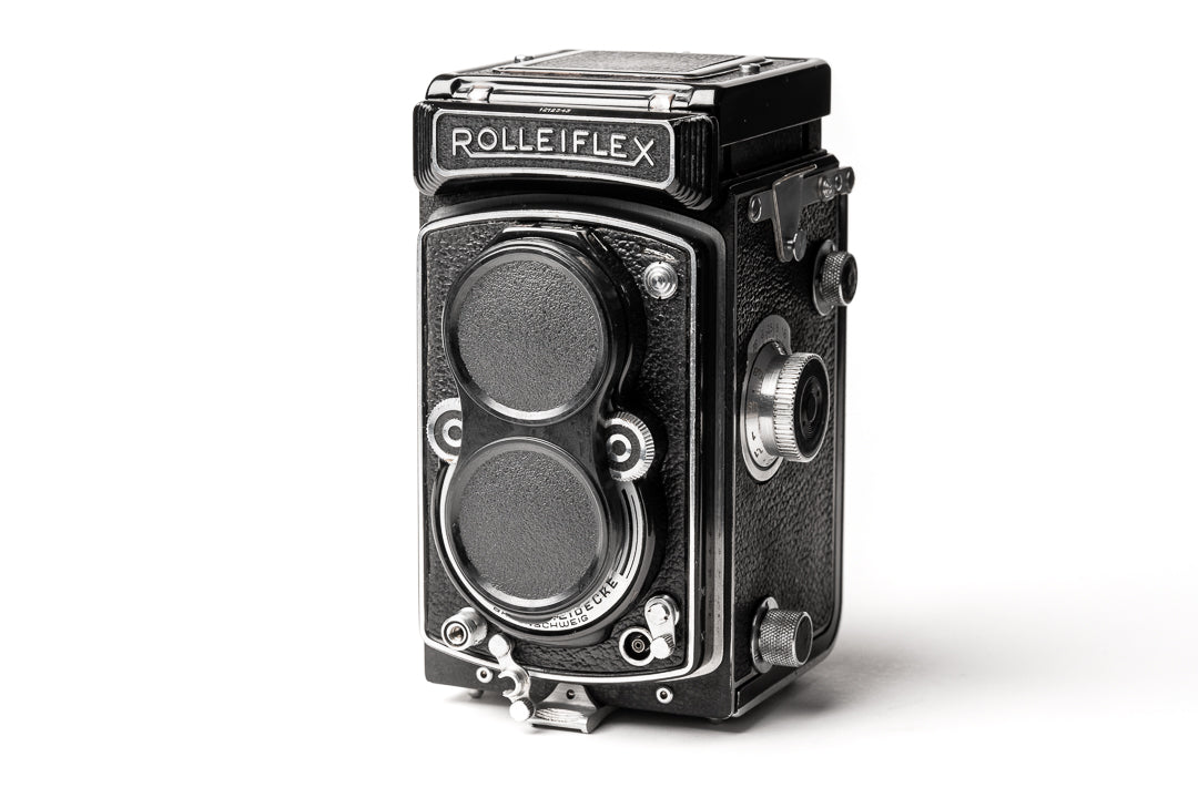 A black plastic lens cap attached to a camera.  Bay 1 I Lens Cap for Rolleicord Rolleiflex Cameras.