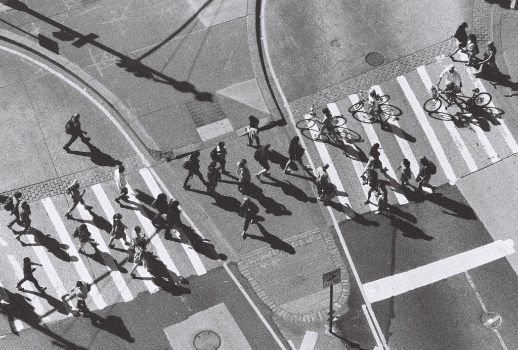 An aerial black and white photo of fast moving pedestrians crossing the street. 