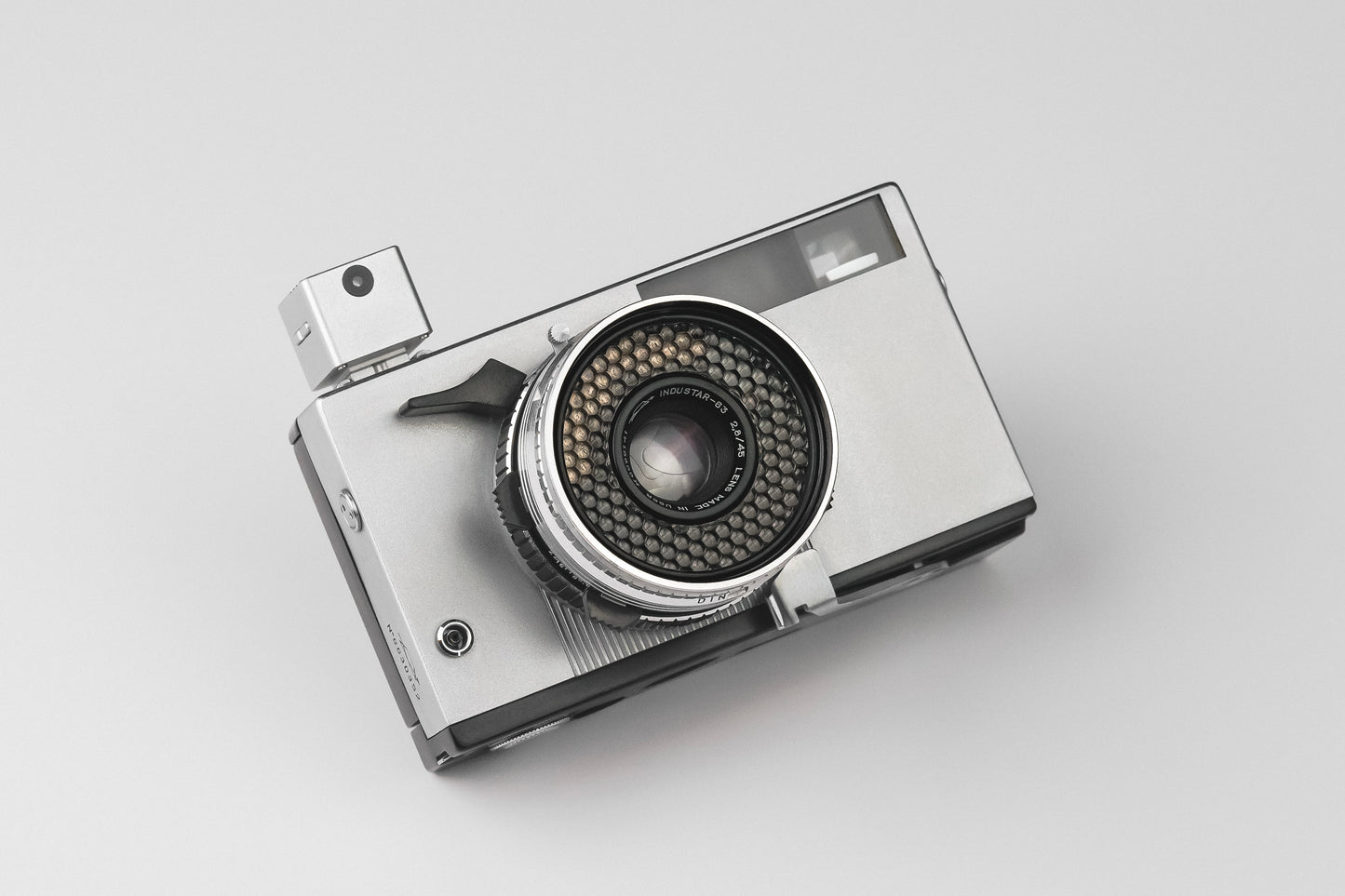 The KMQ chrome model attached to a camera on a white background.