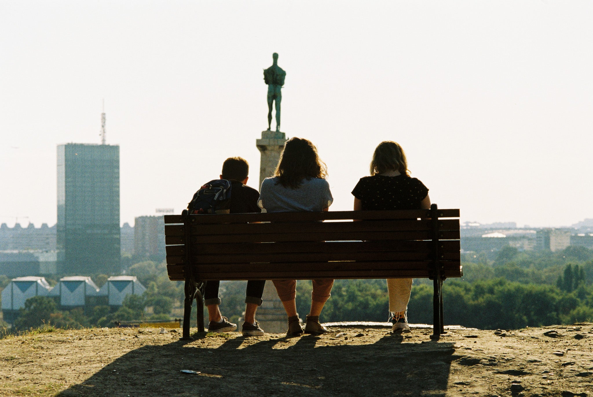 People sitting on a bench with a city skyline on the background. Kodak Gold 200.