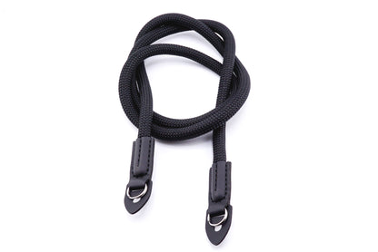 A black rope camera strap on a white background.