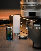 PX32 Battery Adapter with battery, camera and other accessories on a table.
